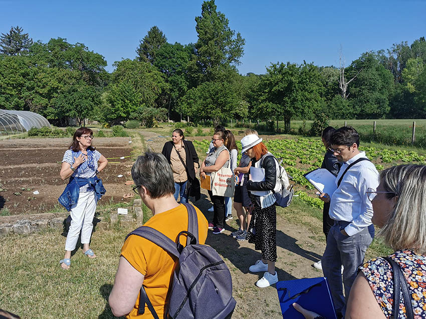 Groupe de personnes dans un jardin en train d'écouter une personne