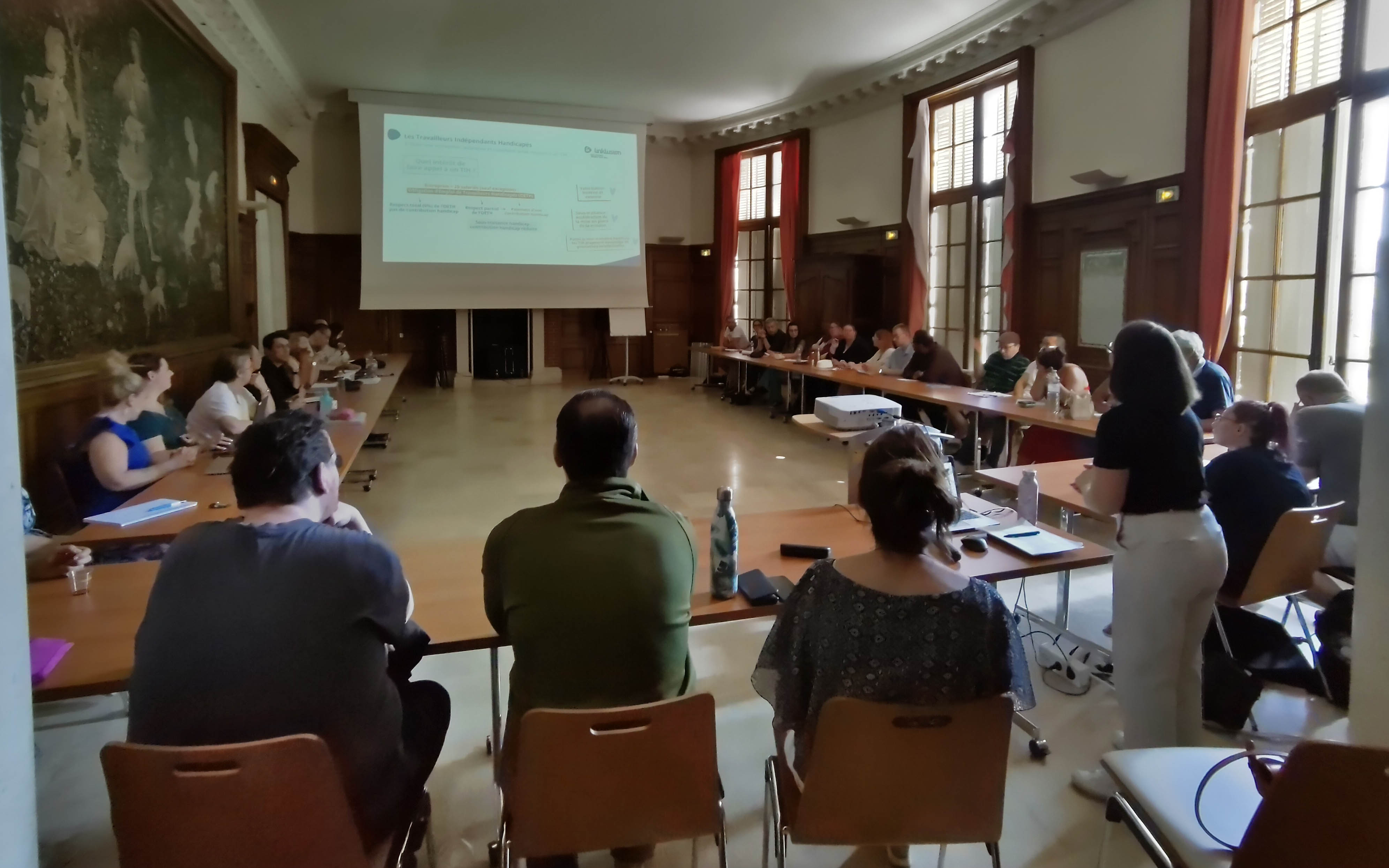 Intervention sur le statut de TIH personnes autour d'une table avec écran et visio conférence
