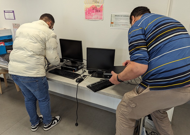 La Recyclerie du COS CRPF fournit du matériel informatique aux GEM Deux personnes en train d'installer des ordinateurs sur une table