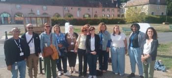 une douzaine de personnes rassemblées regardant l'objectif, en extérieur avec un bâtiment en arrière plan
