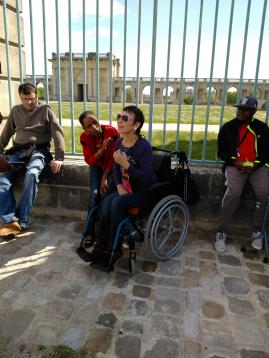 Des résidents du FAM en sortie Un groupe de personnes sont assis devant une grille