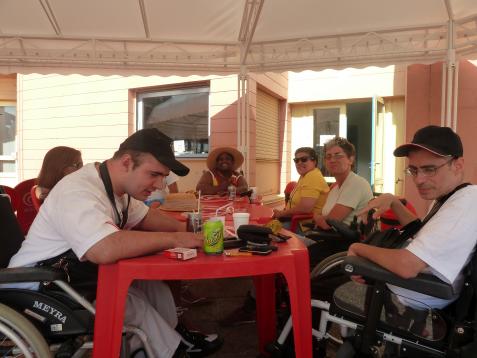 Un groupe de personnes handicapés sont assises autour d'une table sous une tonelle