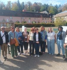 une douzaine de personnes rassemblées regardant l'objectif, en extérieur avec un bâtiment en arrière plan